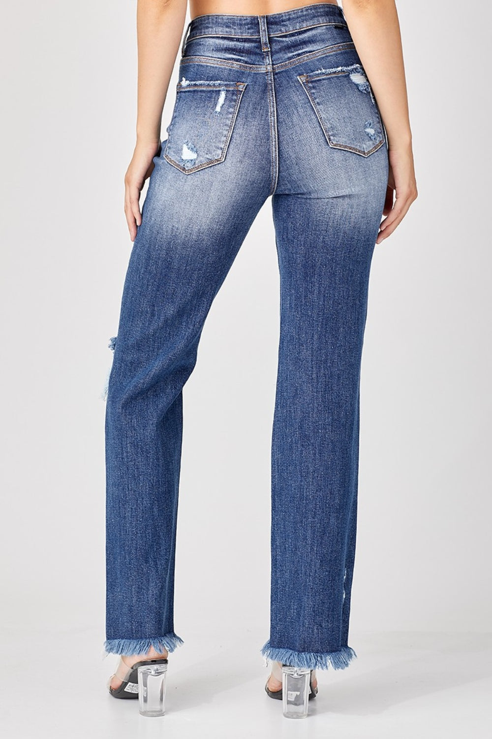 A person is wearing the Risen Full Size Raw Hem Distressed Straight Jeans paired with clear heels.