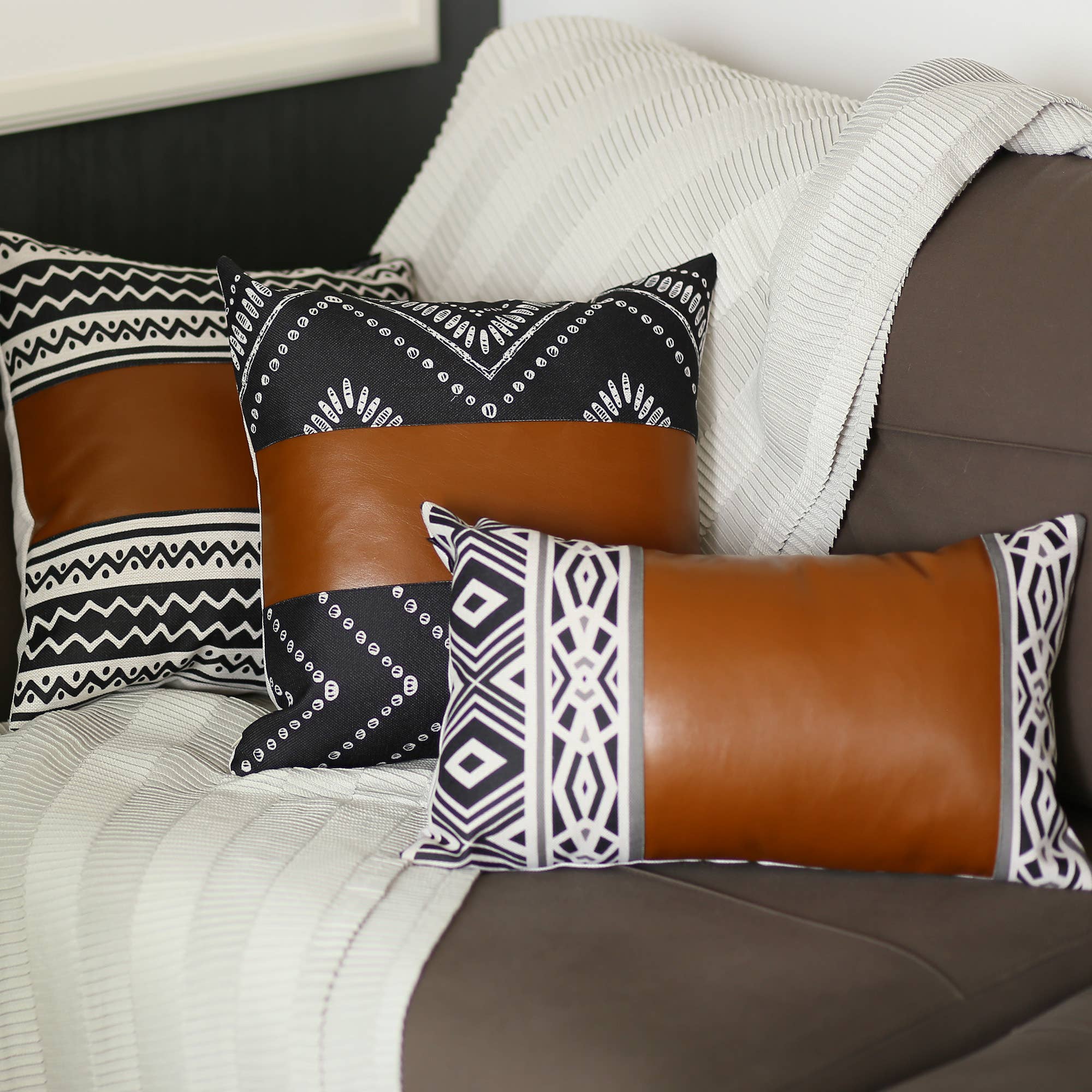 A Bohemian Handmade Decorative Single Throw Pillow featuring a vegan faux leather brown stripe and geometric ivory patterns, set against a beige textured blanket.