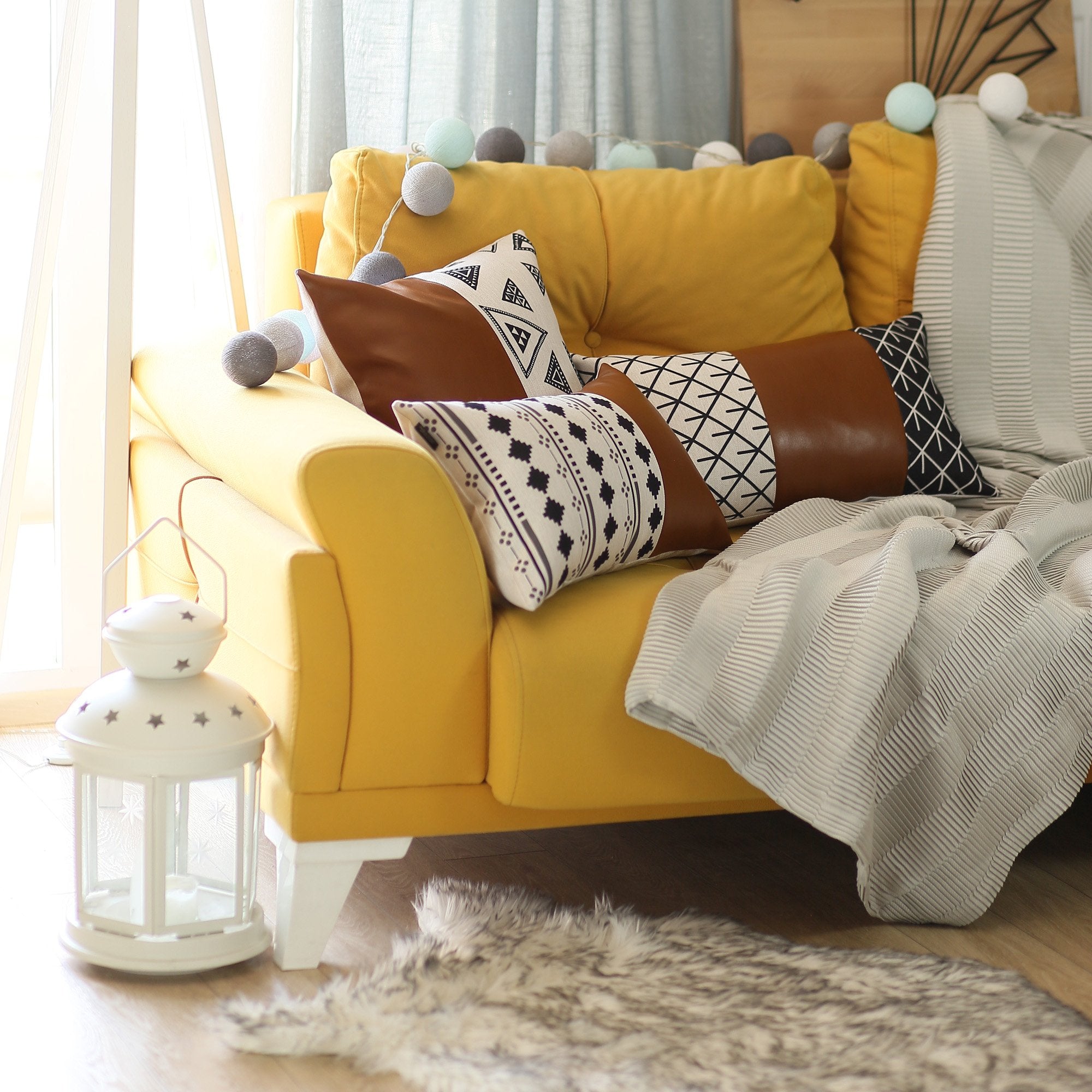 Resting on a yellow cushion is the Bohemian Handmade Decorative Single Throw Pillow, featuring vegan faux leather with a geometric pattern on one half. The setup is completed with round lights draped over it, showcasing the eclectic charm of bohemian throw pillows.