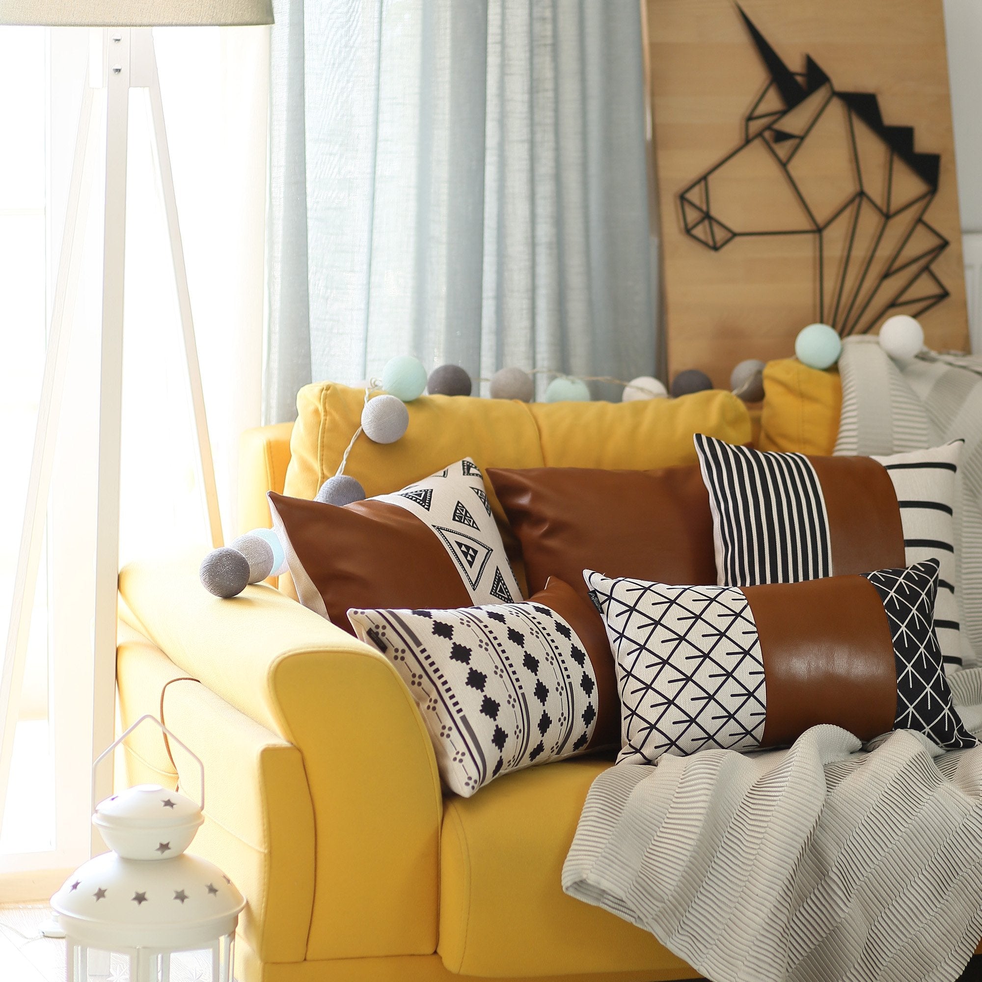 Resting on a yellow cushion is the Bohemian Handmade Decorative Single Throw Pillow, featuring vegan faux leather with a geometric pattern on one half. The setup is completed with round lights draped over it, showcasing the eclectic charm of bohemian throw pillows.