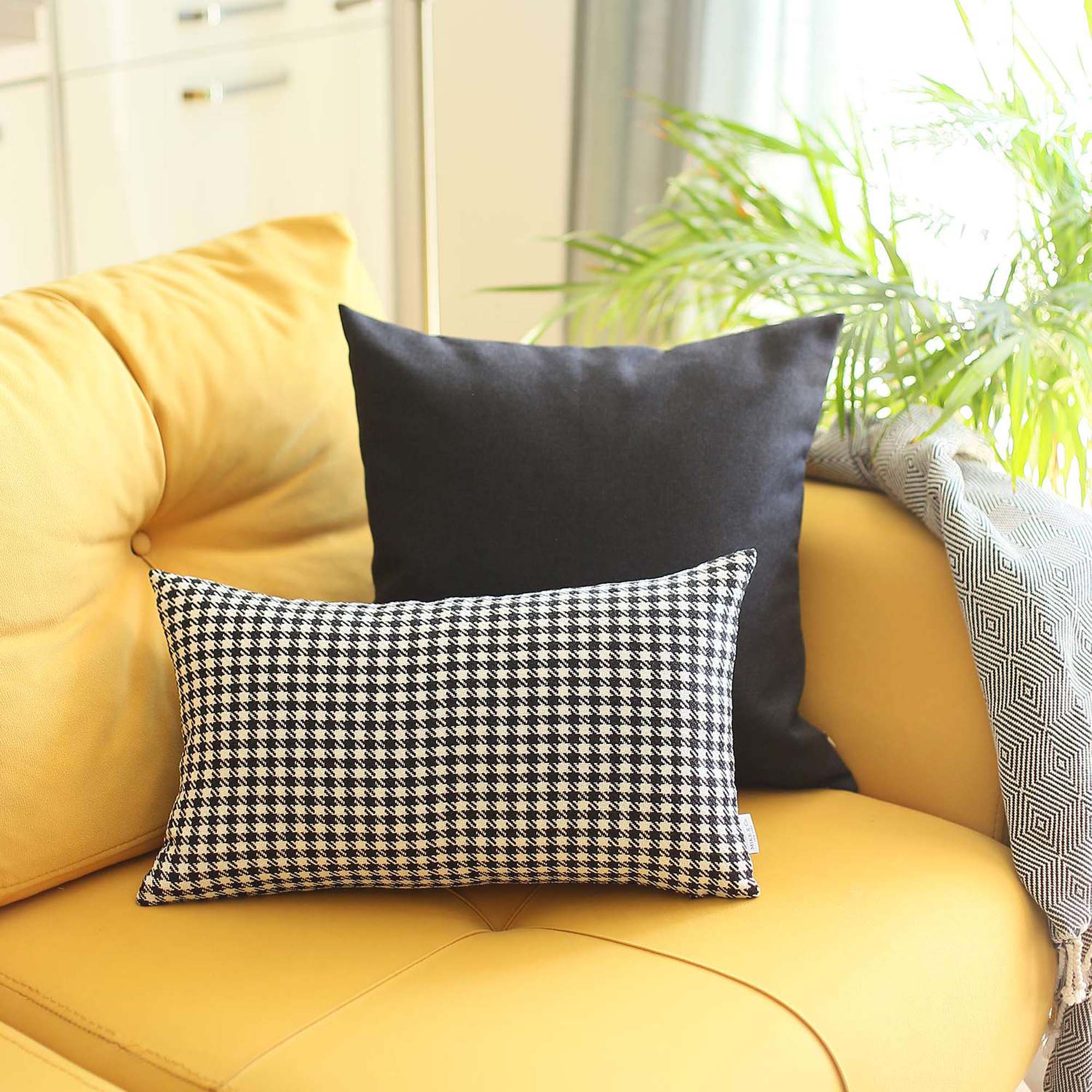 The Bohemian Handmade Decorative Throw Pillow, featuring a houndstooth jacquard design and crafted to OEKO-TEX Standard 100, adds charm to the brown sofa beside a magazine rack.