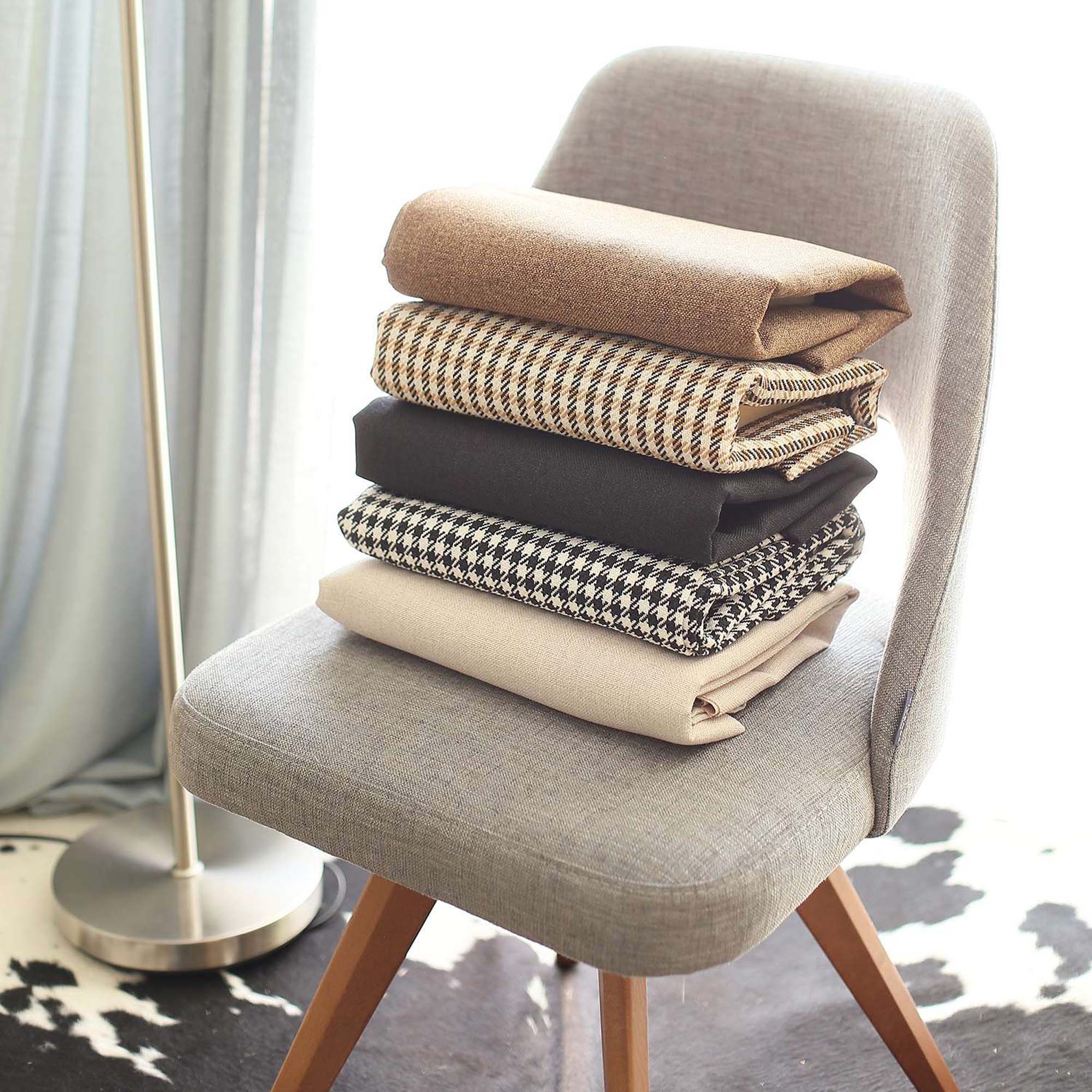 The Bohemian Handmade Decorative Throw Pillow, featuring a houndstooth jacquard design and crafted to OEKO-TEX Standard 100, adds charm to the brown sofa beside a magazine rack.