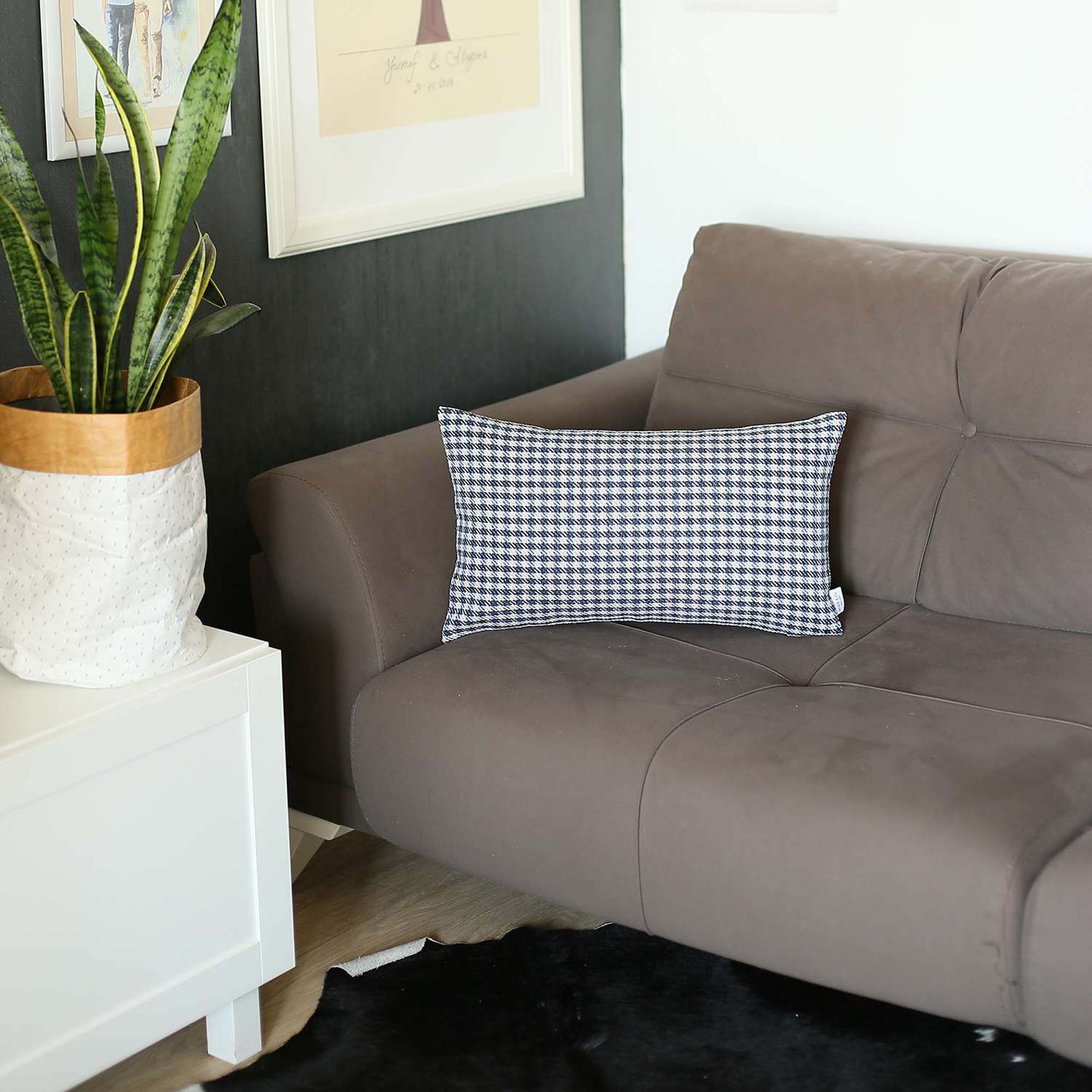 The Bohemian Handmade Decorative Throw Pillow, featuring a houndstooth jacquard design and crafted to OEKO-TEX Standard 100, adds charm to the brown sofa beside a magazine rack.