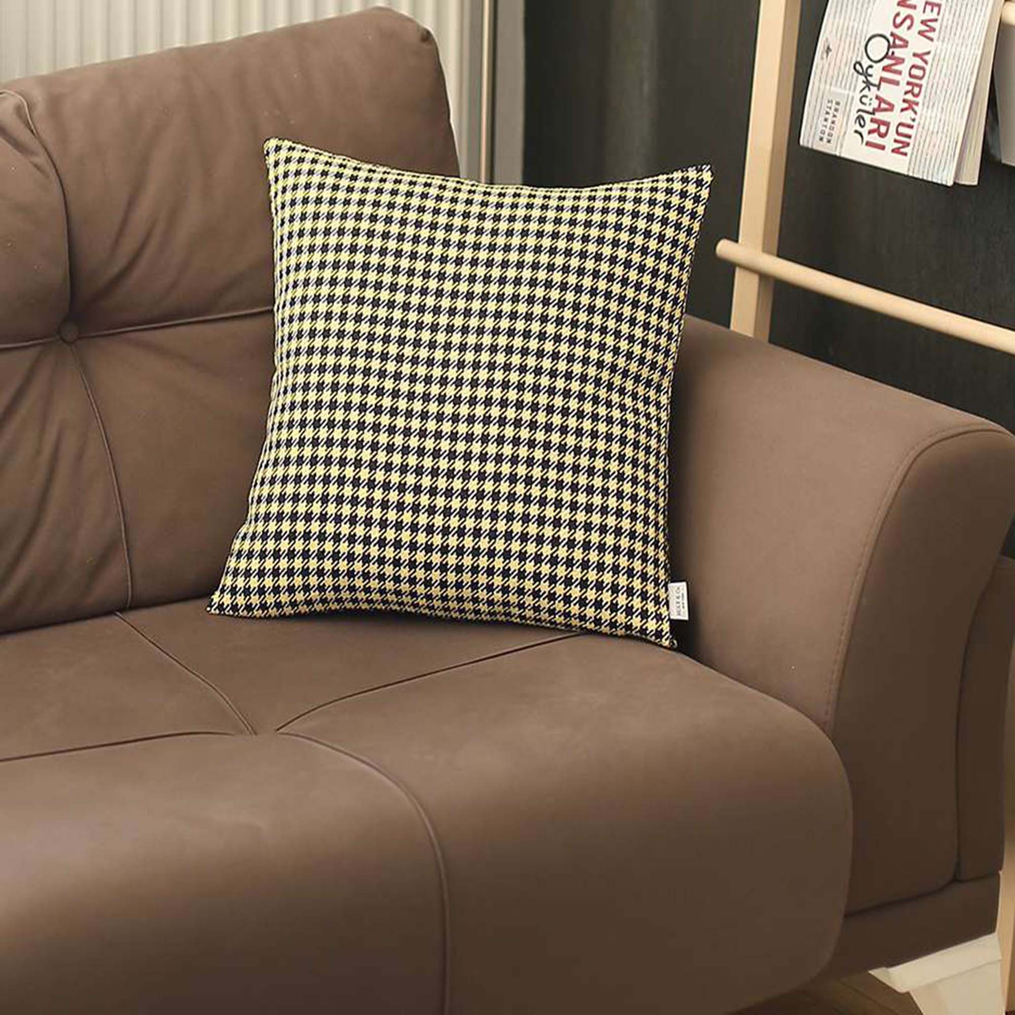 The Bohemian Handmade Decorative Throw Pillow, featuring a houndstooth jacquard design and crafted to OEKO-TEX Standard 100, adds charm to the brown sofa beside a magazine rack.