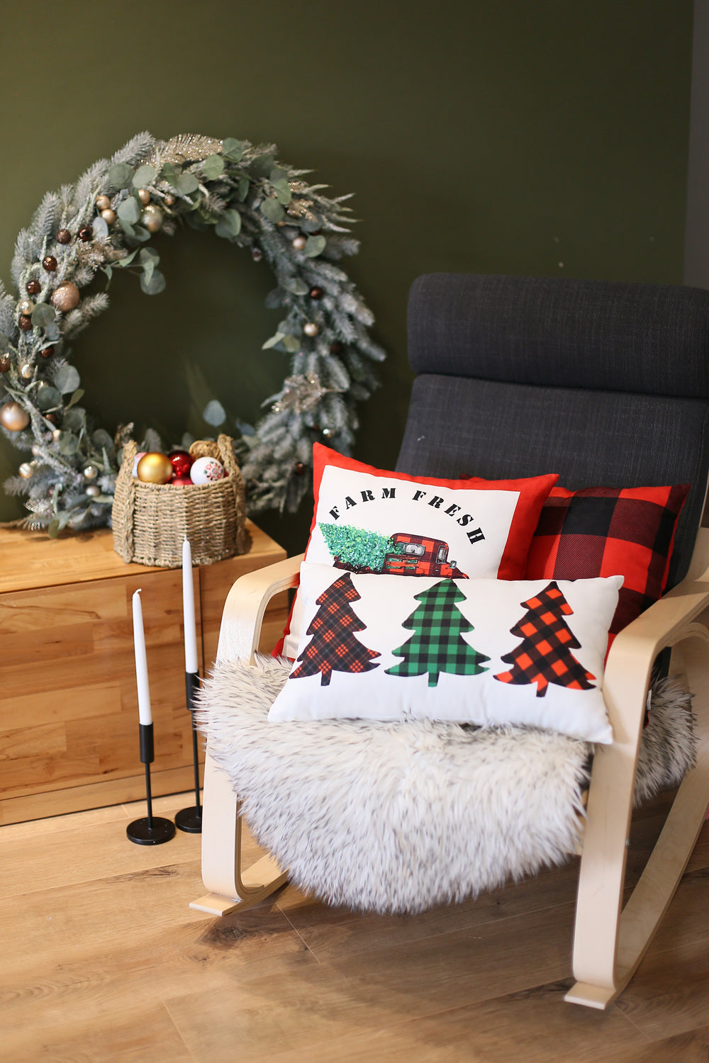 The Christmas Truck Decorative Throw Pillow Set of 4, each measuring 18" x 18" in festive red and white, features a charming design of a red truck carrying a Christmas tree with the "Farm Fresh" text. These pillows are perfect for adding holiday warmth to your sofa or bedding. The cozy setup is enhanced by a basket and fur blanket on the floor, while other festive decor brightens the background. Conveniently machine washable pillow inserts make this an ideal choice for your holiday decor.