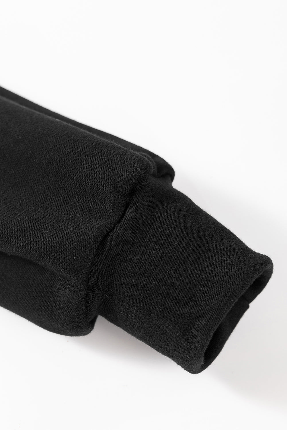 A person wearing a Black Bowknot Dewback Round Neck Sweatshirt, white pants, and a light-colored cap stands against a pink background. The individual has one hand on their hip and is looking down.