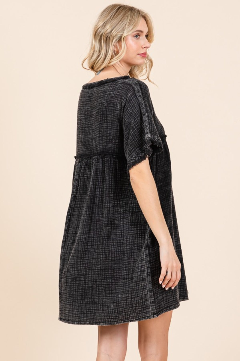 A person is wearing the Culture Code Full Size Short Sleeve Babydoll Texture Dress with Pockets, in black, standing against a plain background.