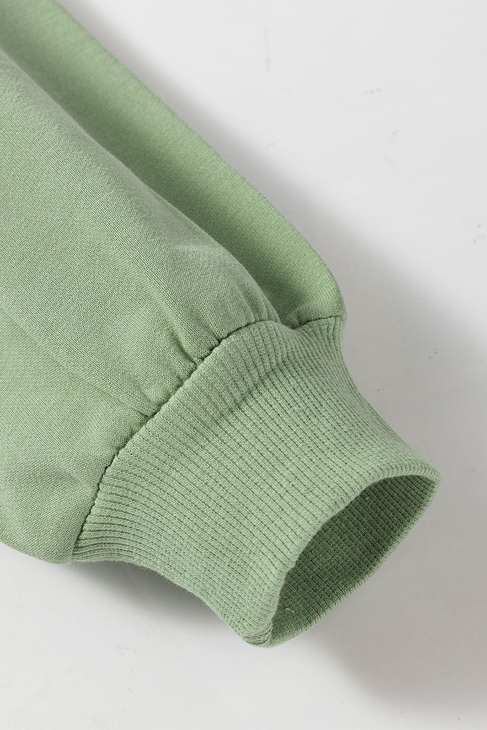 A person wearing a Grass Green Leopard Print Colorblock Raglan Sleeve Sweatshirt stands in front of a brick wall.