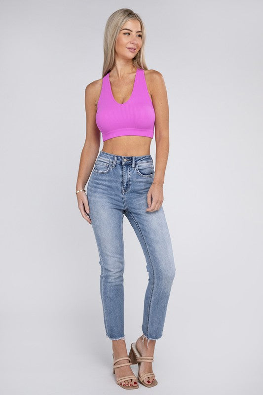 Woman wearing a pink Lanae Ribbed Cropped Racerback Tank Top and blue jeans standing against a neutral background.