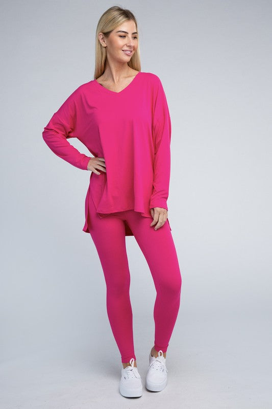 Clad in the Brushed DTY Microfiber Loungewear Set, a person stands against a plain background, showcasing its buttery soft, bright pink long-sleeve top and matching leggings, complemented by white sneakers.