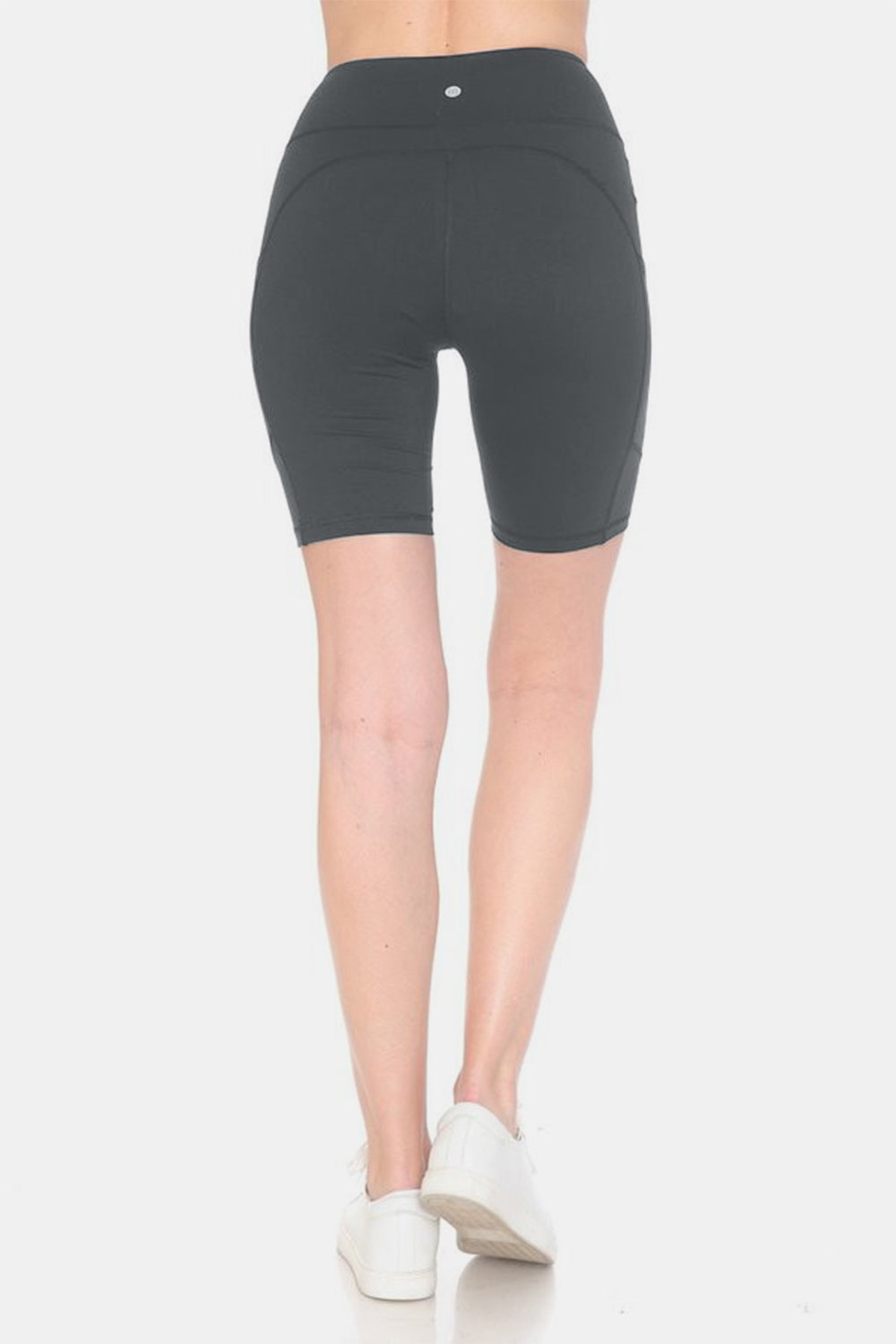 Person placing a smartphone into the side pocket of stylish activewear, featuring Leggings Depot Full Size High Waist Active Shorts made from moisture-wicking fabric.