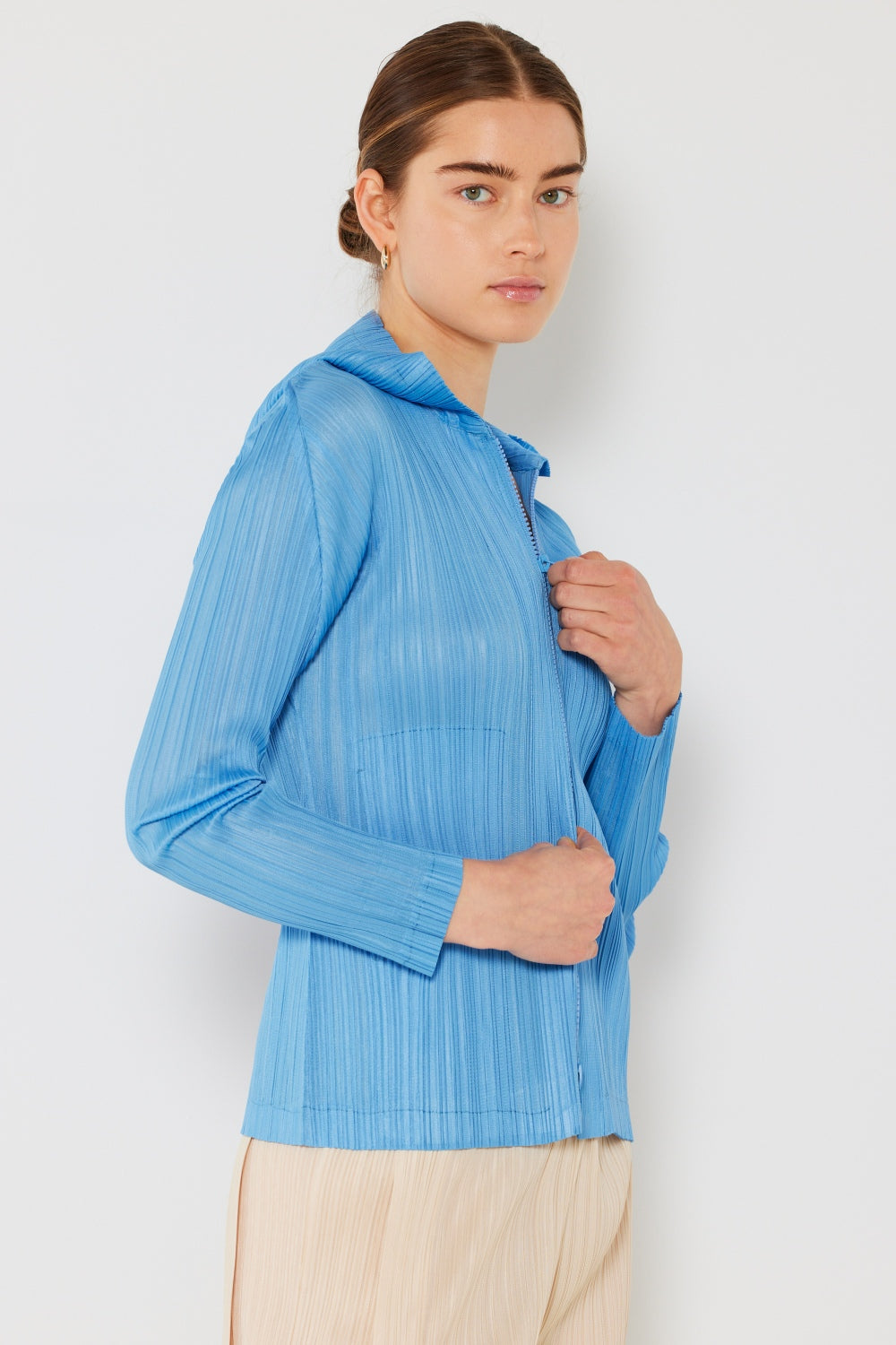 A person wearing the Marina West Swim Pleated Hood Jacket with hands in pockets, showcasing its convenient 2-way zipper, stands against a plain white background.