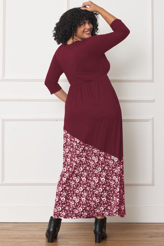 A woman with curly hair wears an Asymmetrical Leopard Accent Maxi Dress paired with black boots, and stands in front of a white paneled wall.