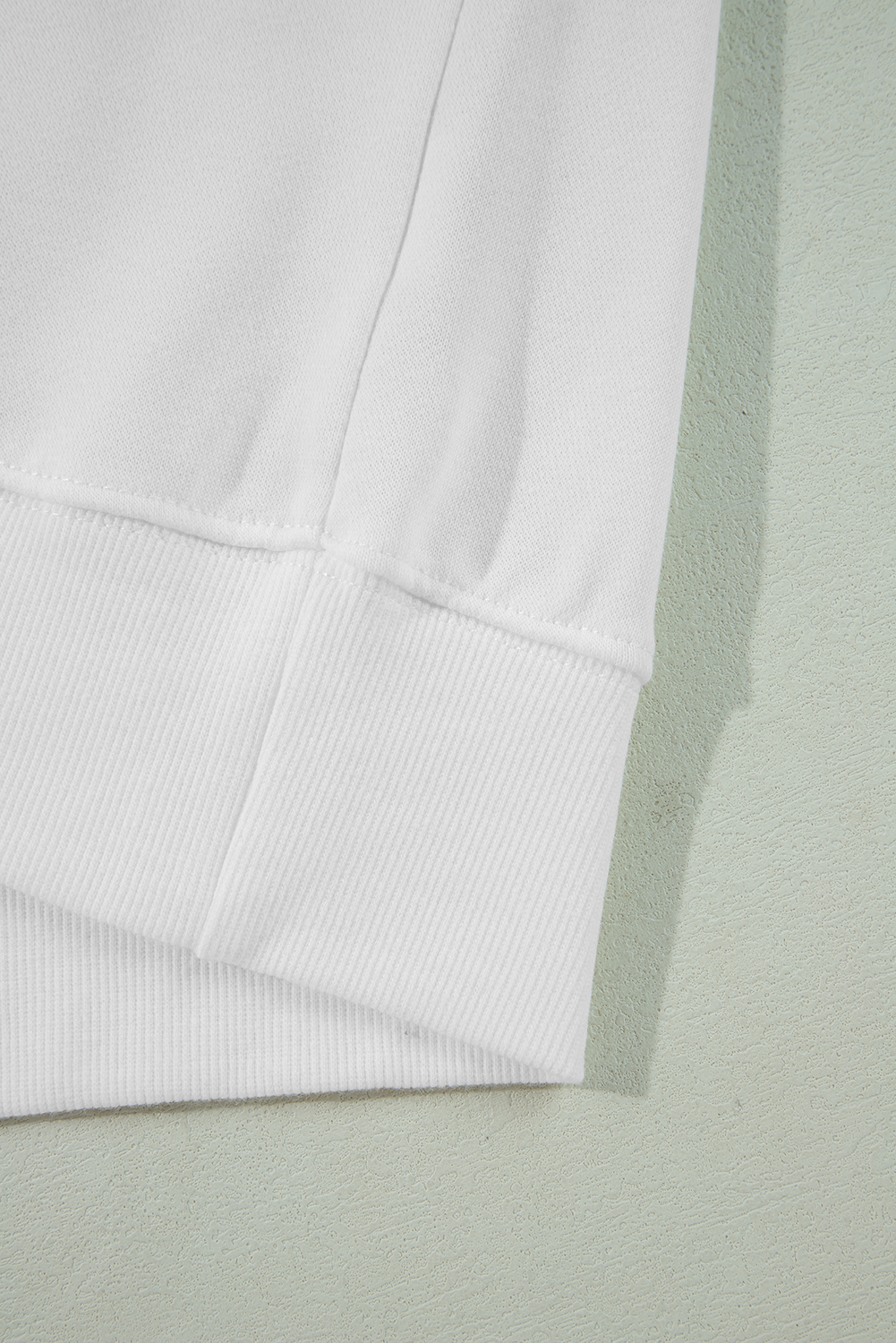 A person with long blonde hair is wearing a White BIRTHDAY QUEEN Graphic Balloon Sleeve Sweatshirt, paired with a pink feathered skirt, and sitting against a beautifully decorated backdrop.