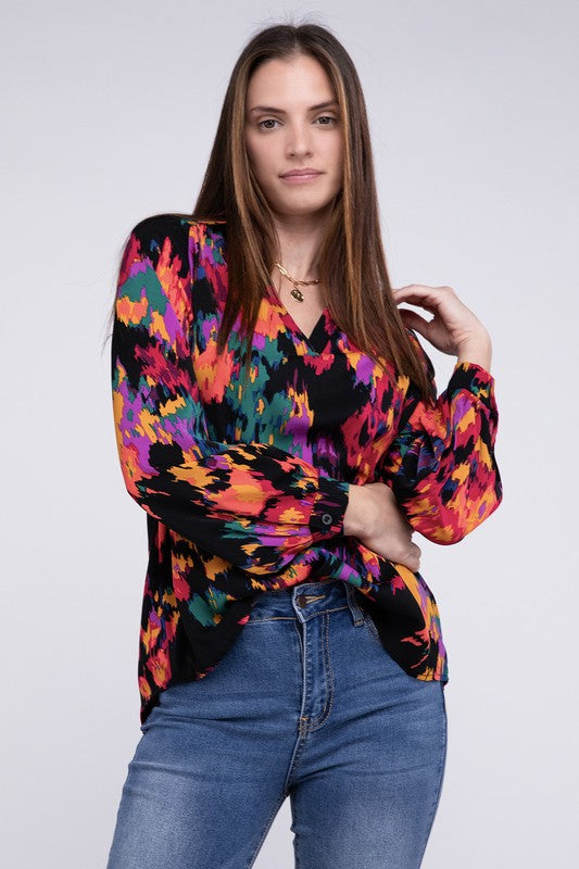 A person dressed in a vibrant Floral Raglan Sleeve Blouse featuring a V-neck stands against a plain backdrop, paired with jeans.