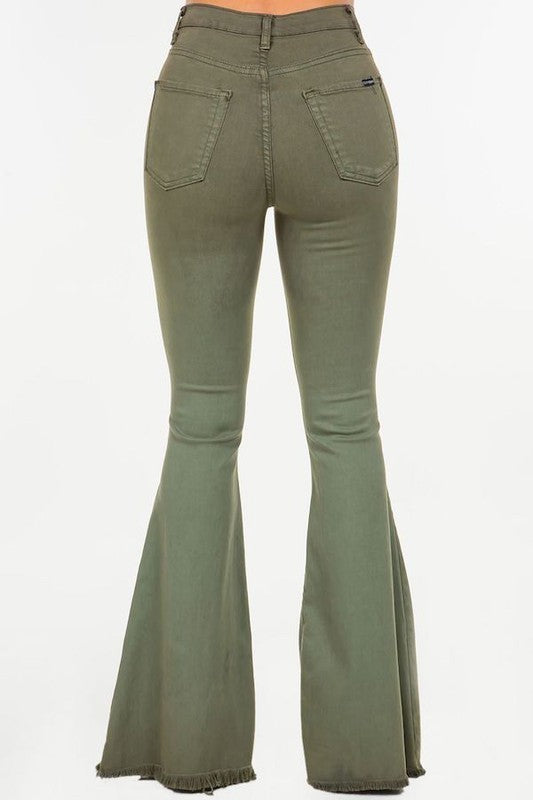 A person wearing the Bell Bottom Jean in Olive, high-rise pants with a 30" inseam, made in the USA, with their torso and feet partially visible against a plain background.