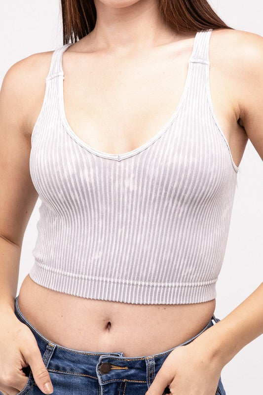 A woman in a Washed Ribbed Cropped V-Neck Tank Top and jeans posing with her hand on her head against a plain background.