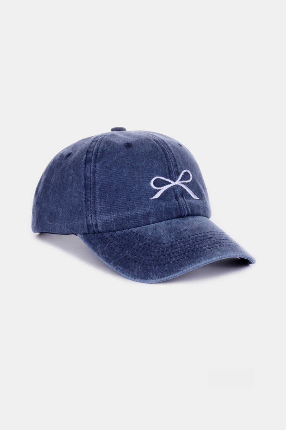 The Zenana Bow Embroidered Washed Cotton Cap features a pink design with a stylish white bow on the front, set against a plain, light background. This chic accessory seamlessly combines elegance and sportiness.