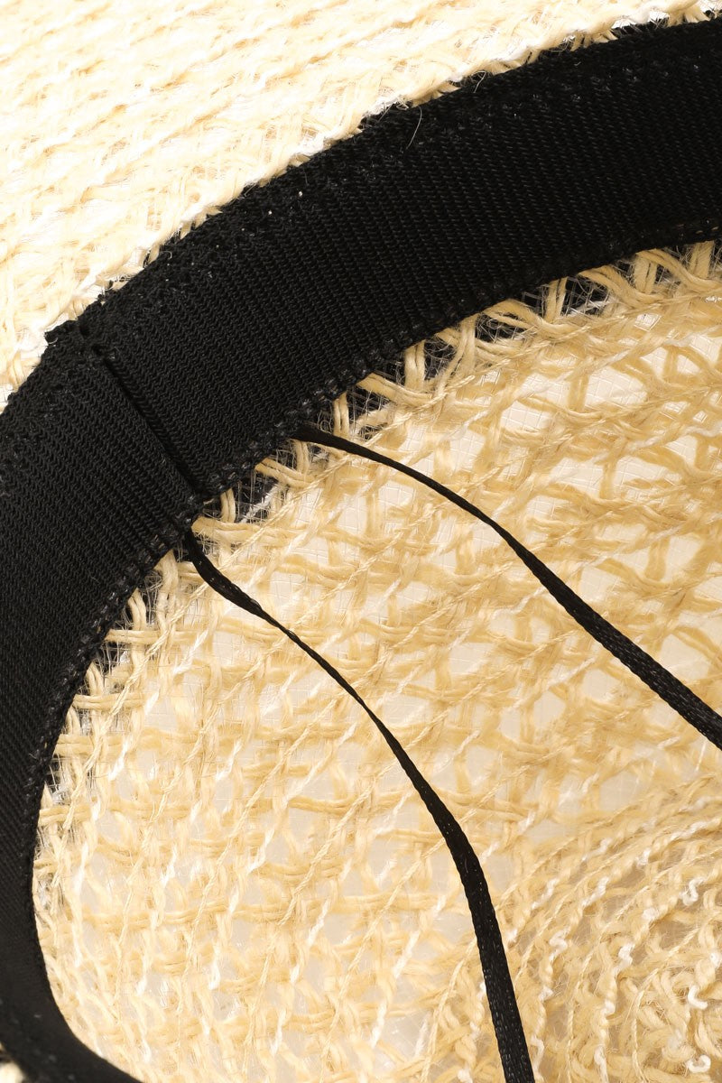 The Fame Wide Brim Straw Weave Sun Hat is designed with a wide brim and adorned with a black ribbon band, providing both stylish flair and superior sun protection.