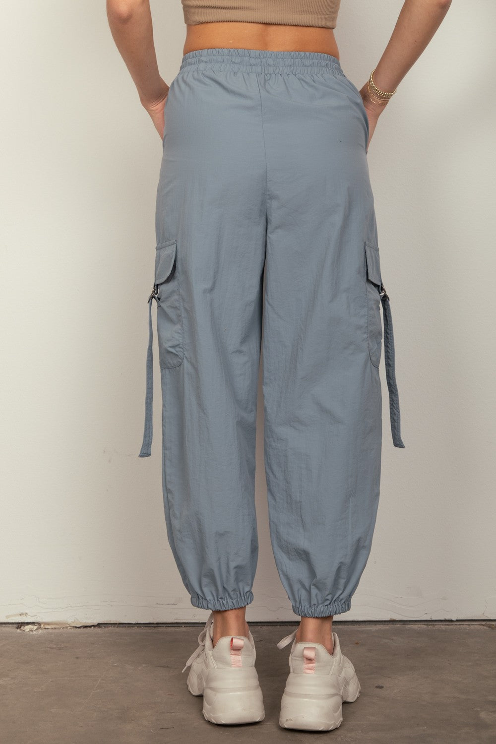 Person wearing VERY J Elastic Waist Woven Cargo Pants in light blue with hands in pockets, paired with white sneakers, standing against a plain background.