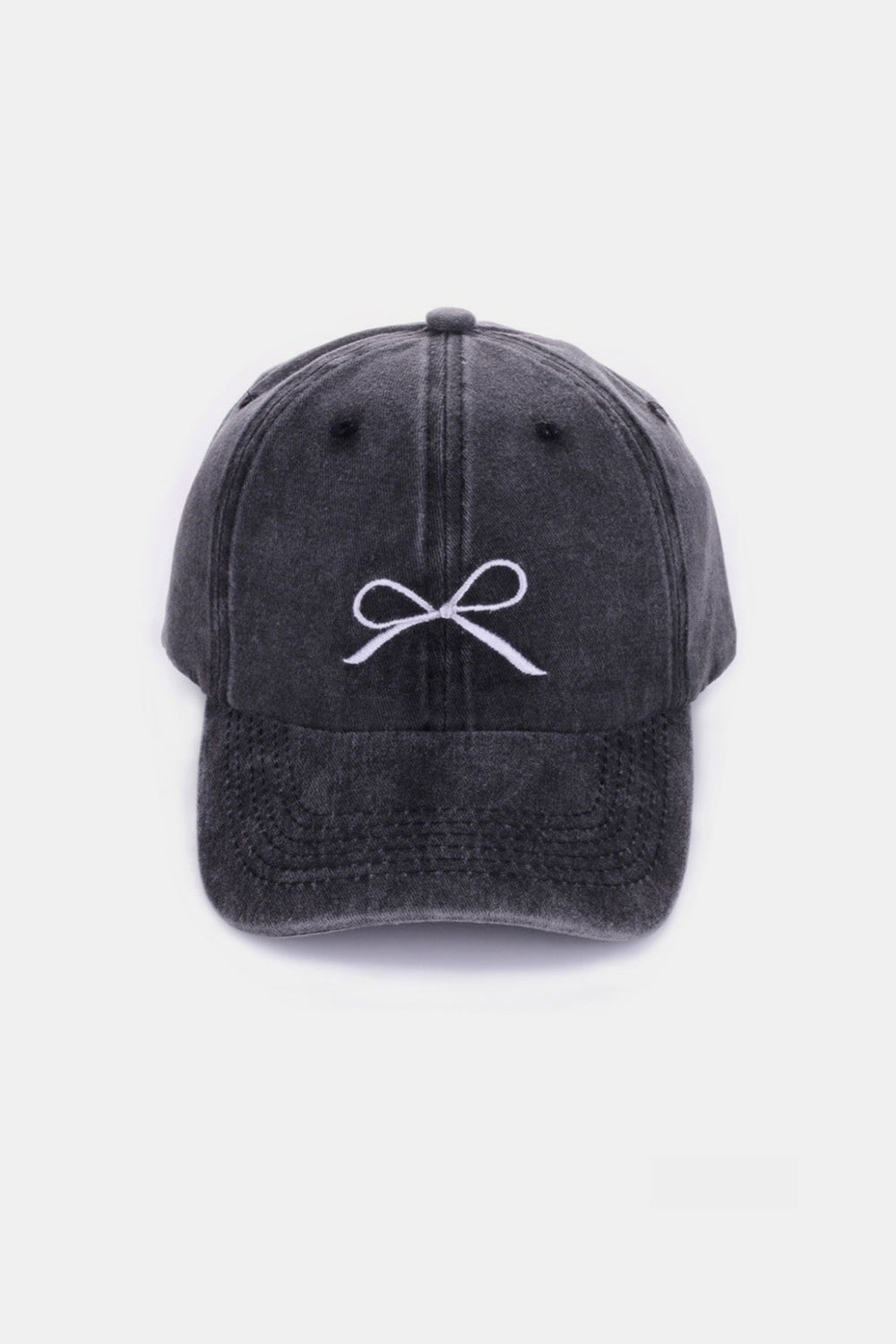 The Zenana Bow Embroidered Washed Cotton Cap features a pink design with a stylish white bow on the front, set against a plain, light background. This chic accessory seamlessly combines elegance and sportiness.