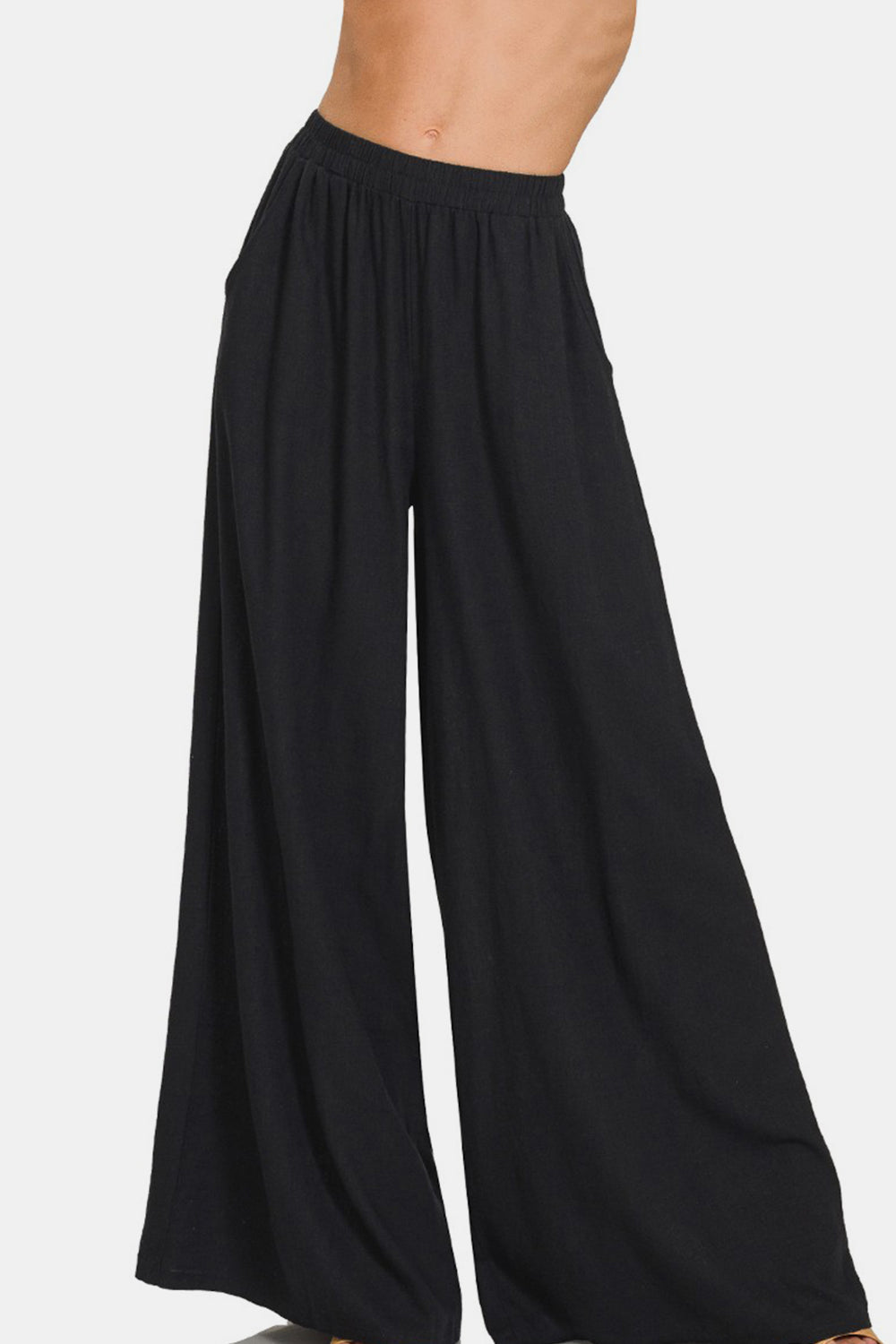 A person wearing Zenana Pleated Linen Blend Wide Leg Pants with an elastic waistband. The chic addition of these wide-leg silhouette pants is evident, even though the image is cropped at the torso and feet.