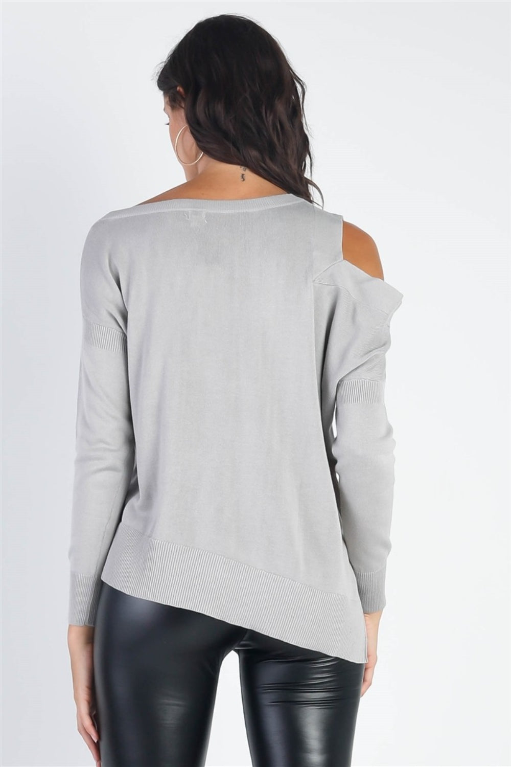 A person wearing the UNIQ Cold Shoulder Long Sleeve Knit Top in black and distressed denim shorts stands against a plain white background, effortlessly showcasing a versatile wardrobe choice.