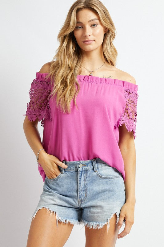 A woman in a bohemian-inspired Crochet Lace Sleeveless Accent Off Shoulder Top and white shorts stands indoors, looking to the side.