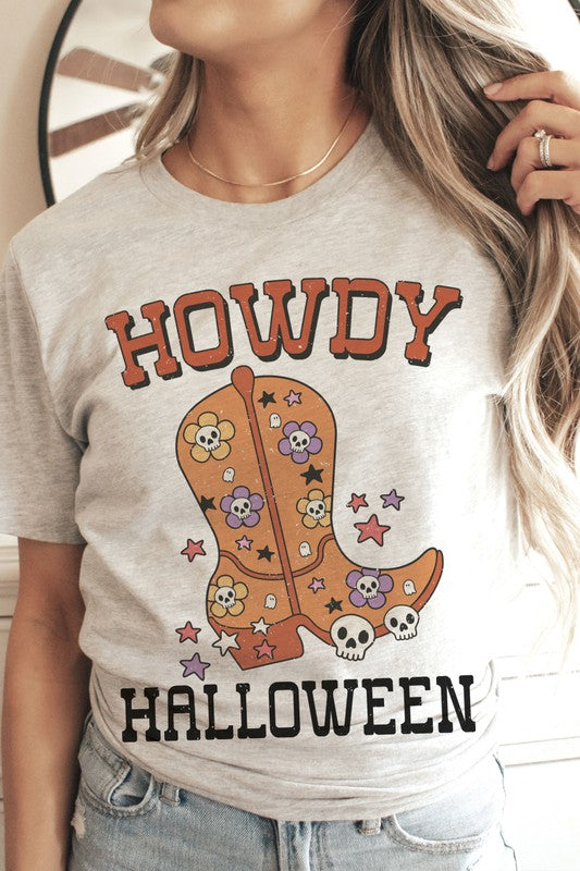 Person wearing the HOWDY HALLOWEEN Graphic Tee, a 100% cotton white t-shirt featuring the words "Howdy Halloween" along with a decorative boot embellished with skulls and flowers.