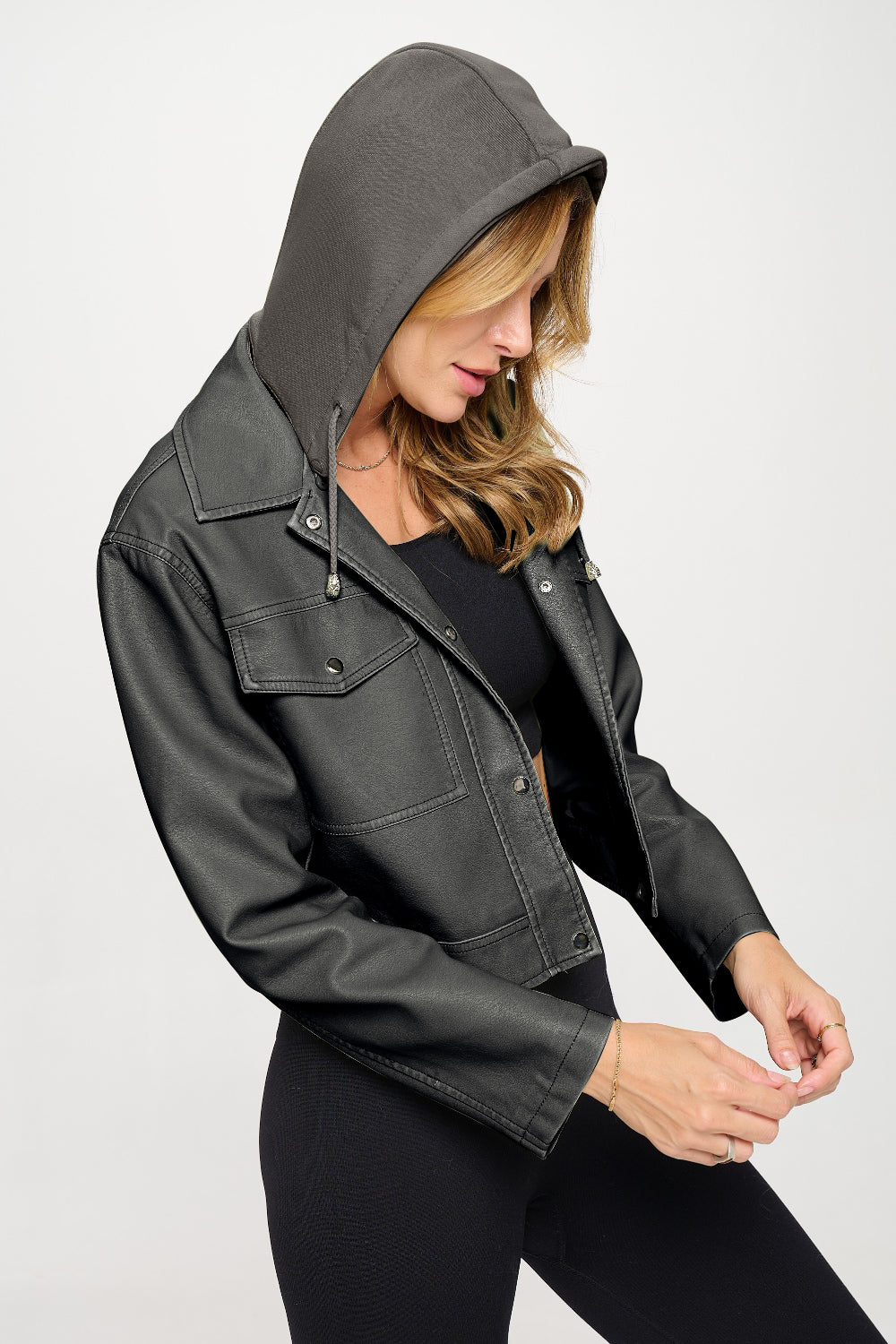 Person wearing the Coalition LA Snap Down Cropped Hooded Jacket over a black outfit, posing against a plain white background.