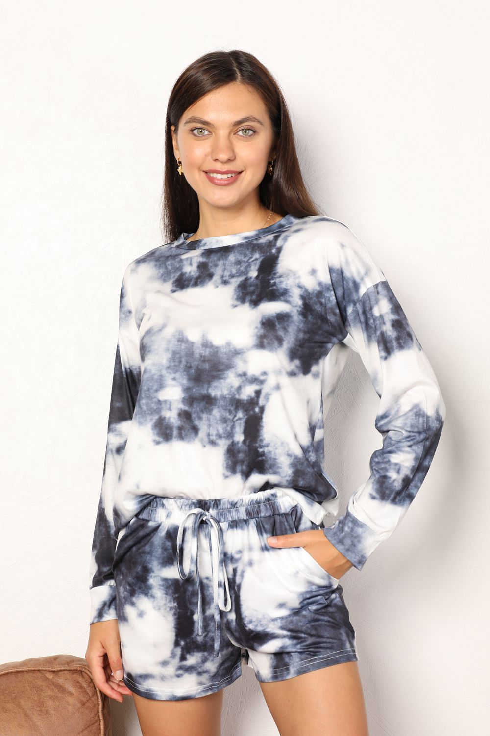 A person is standing and smiling while wearing the Shiny Tie-Dye Round Neck Top and Shorts Lounge Set, which features a matching black-and-white tie-dye pattern with a long-sleeve shirt and shorts.