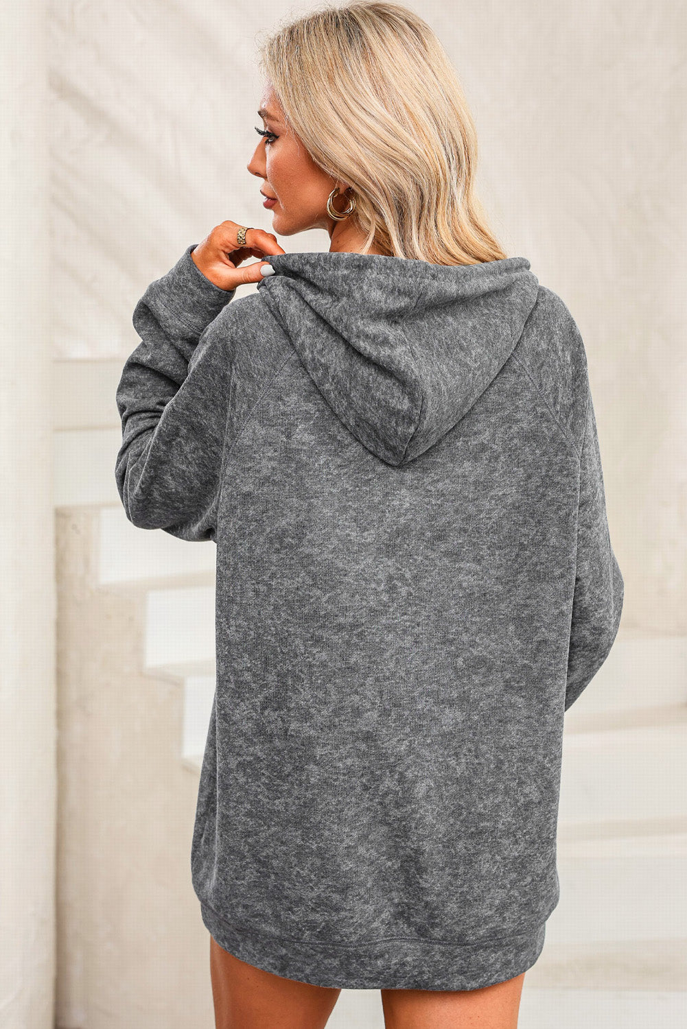 A person with blonde hair is standing with their back to the camera, wearing a Gray Mineral Wash Kangaroo Pocket Drawstring Pullover Hoodie.