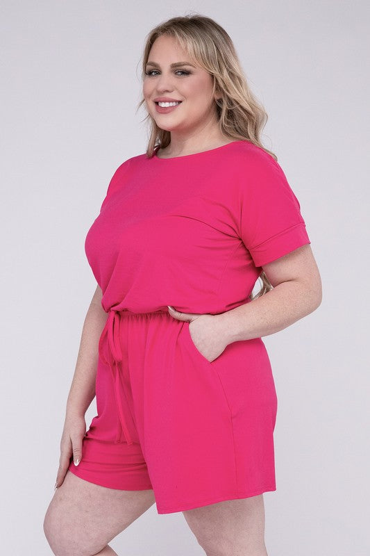 A person is wearing the Plus Brushed DTY Romper with Pockets in bright pink, smiling as they pose with one hand on their head and the other tucked into a pocket, all set against a gray background.