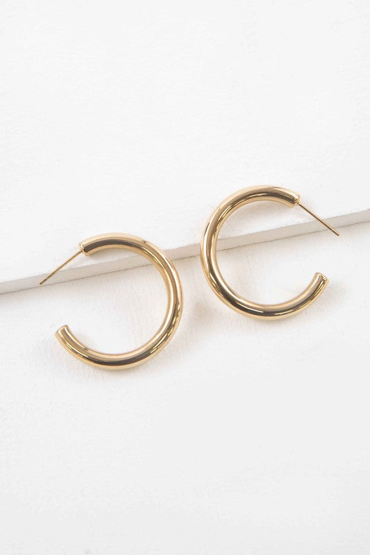 The Canal Hoop Earrings, with their lustrous 14k gold plating, are artfully displayed on a white background, highlighting their hypoallergenic allure.