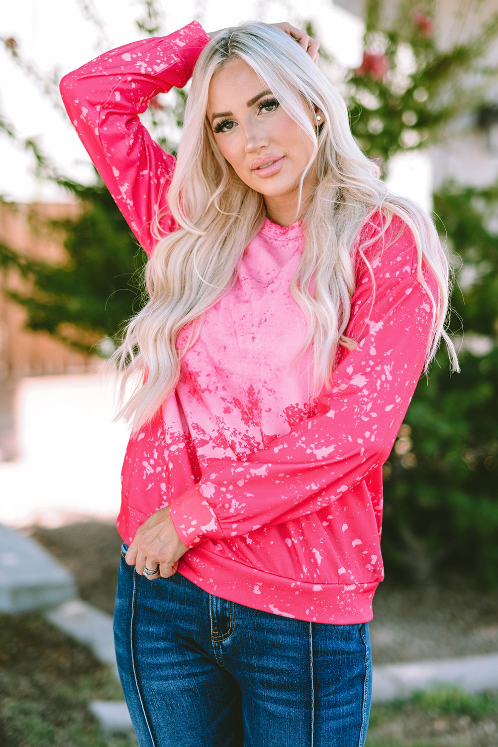 Person with long blonde hair wearing a Rose Tie Dye Long Sleeve Pullover Sweatshirt and blue jeans, standing outdoors with back to the camera.