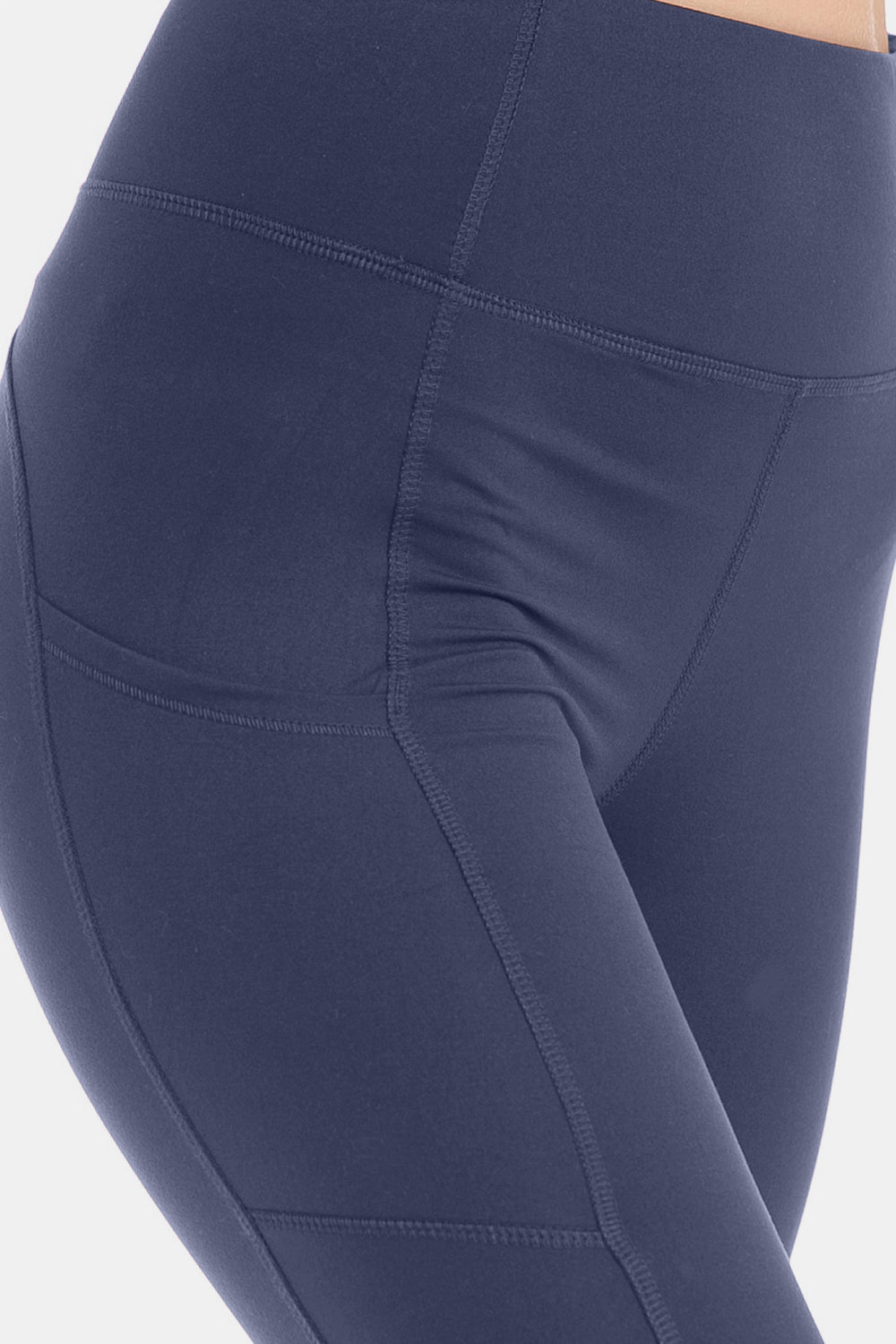 A person is shown from the side wearing Leggings Depot High Waist Wide Waistband Leggings in navy blue, which feature convenient pockets and are paired with white sneakers. The stretchy fabric of the leggings adds comfort and flexibility to their active look.