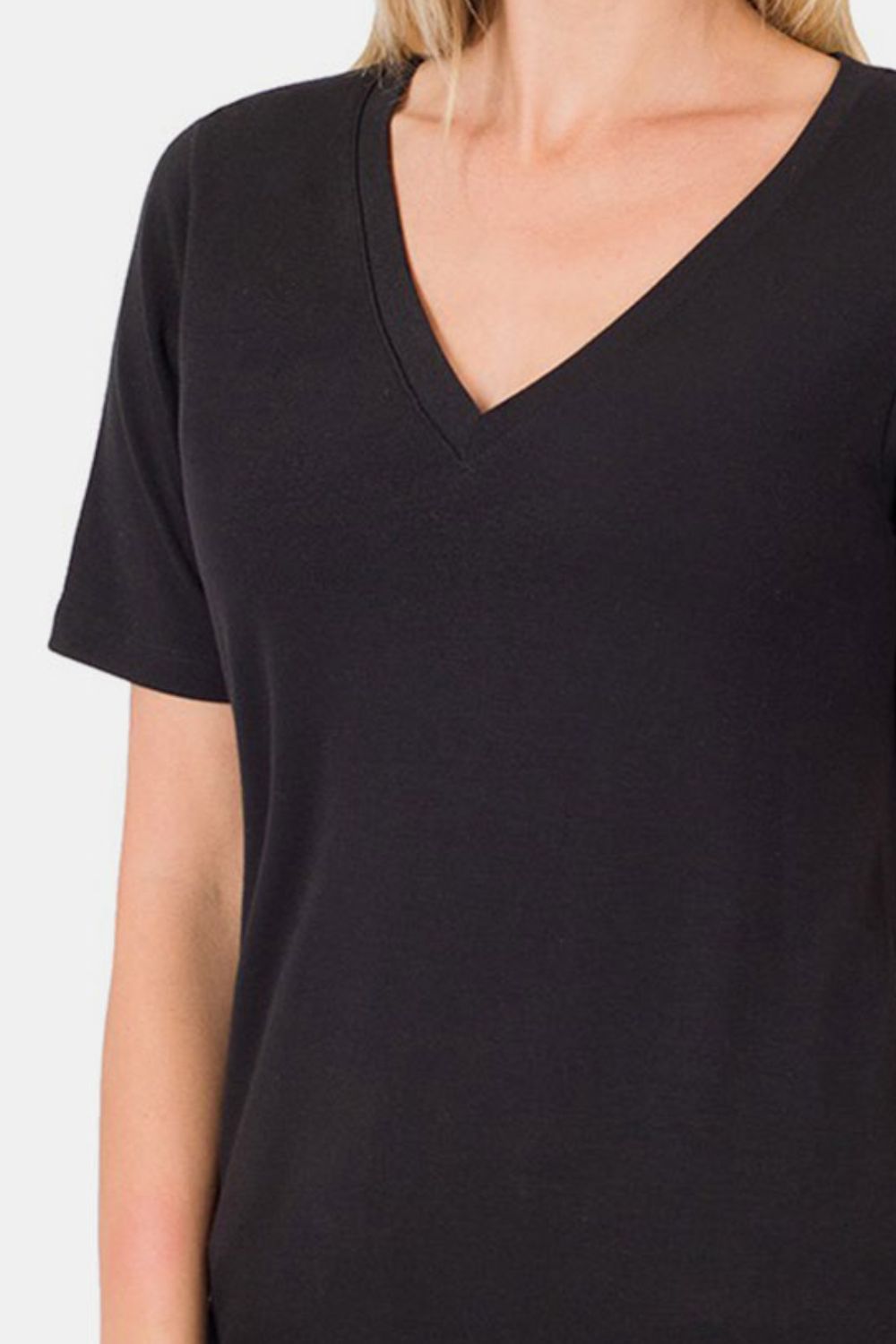 A woman with blonde hair is wearing the Zenana V-Neck Short Sleeve T-Shirt in black, made of breathable fabric, paired with blue jeans. She is standing against a plain white background, smiling. Perfect for everyday wear.