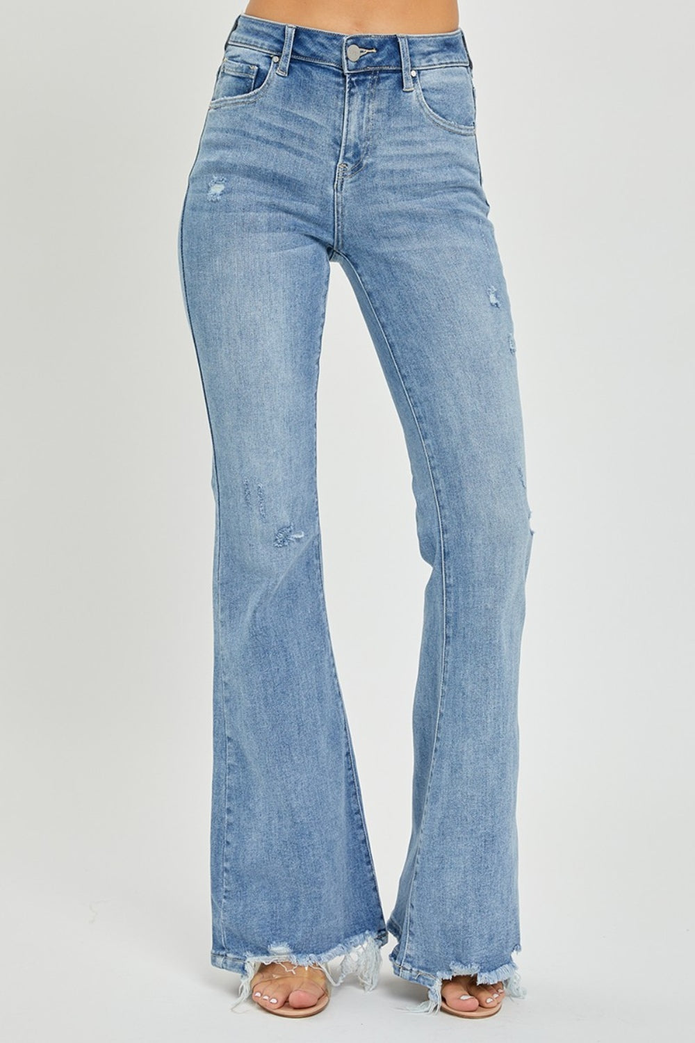 A person wearing the Risen Full Size High Rise Frayed Hem Flare Jeans in light blue with distressed details.