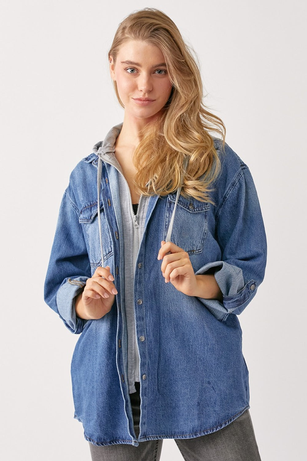 A person with long hair wears a casual oversized grey hooded sweatshirt under a RISEN Zip Up Hooded Denim Shirt.