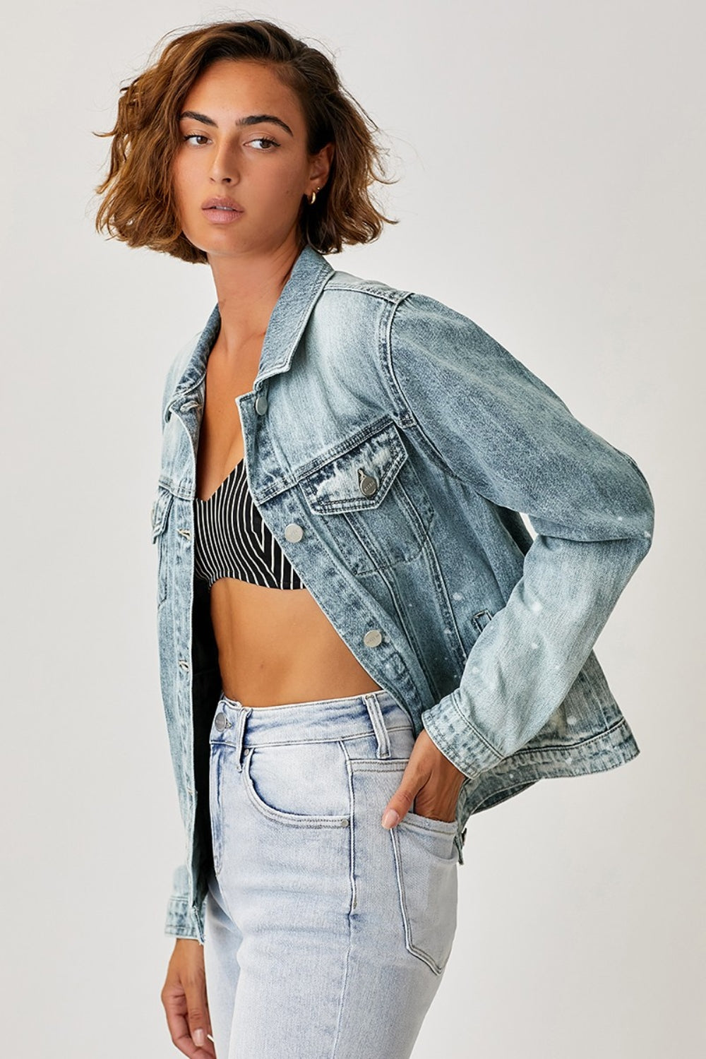 Person wearing the RISEN Button Up Ombre Washed Jacket over a black and white striped top, paired with light-wash jeans, posing against a plain backdrop.