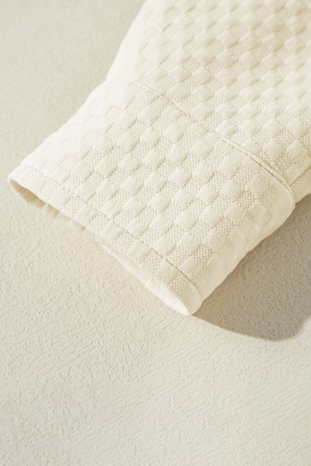 A person stands indoors facing away, wearing the Apricot Textured Buttoned Neckline Side Pockets Hoodie and black shorts. Their hand rests on their hip.