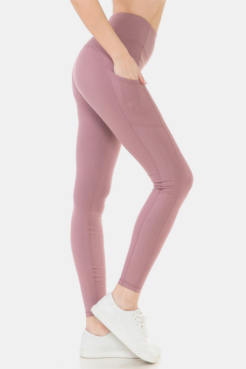 Side view of an individual wearing Leggings Depot Wide Waistband High Waist Leggings in mauve, ideal for high-intensity workouts, with one hand in the pocket and white sneakers, standing against a plain white background.