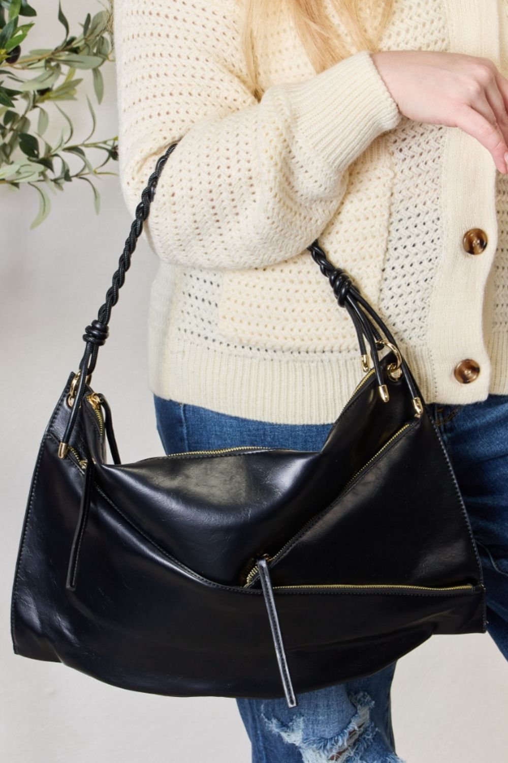 A person in a cream sweater holds a medium-size SHOMICO Zipper Detail Shoulder Bag with gold metal zipper pockets.