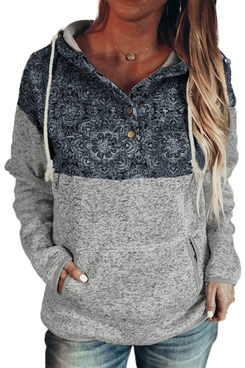 A person with long blonde hair is wearing a Gray Tribal Print Vintage Pocket Hoodie. They are turned sideways, and pampas grass in a vase is visible in the background.