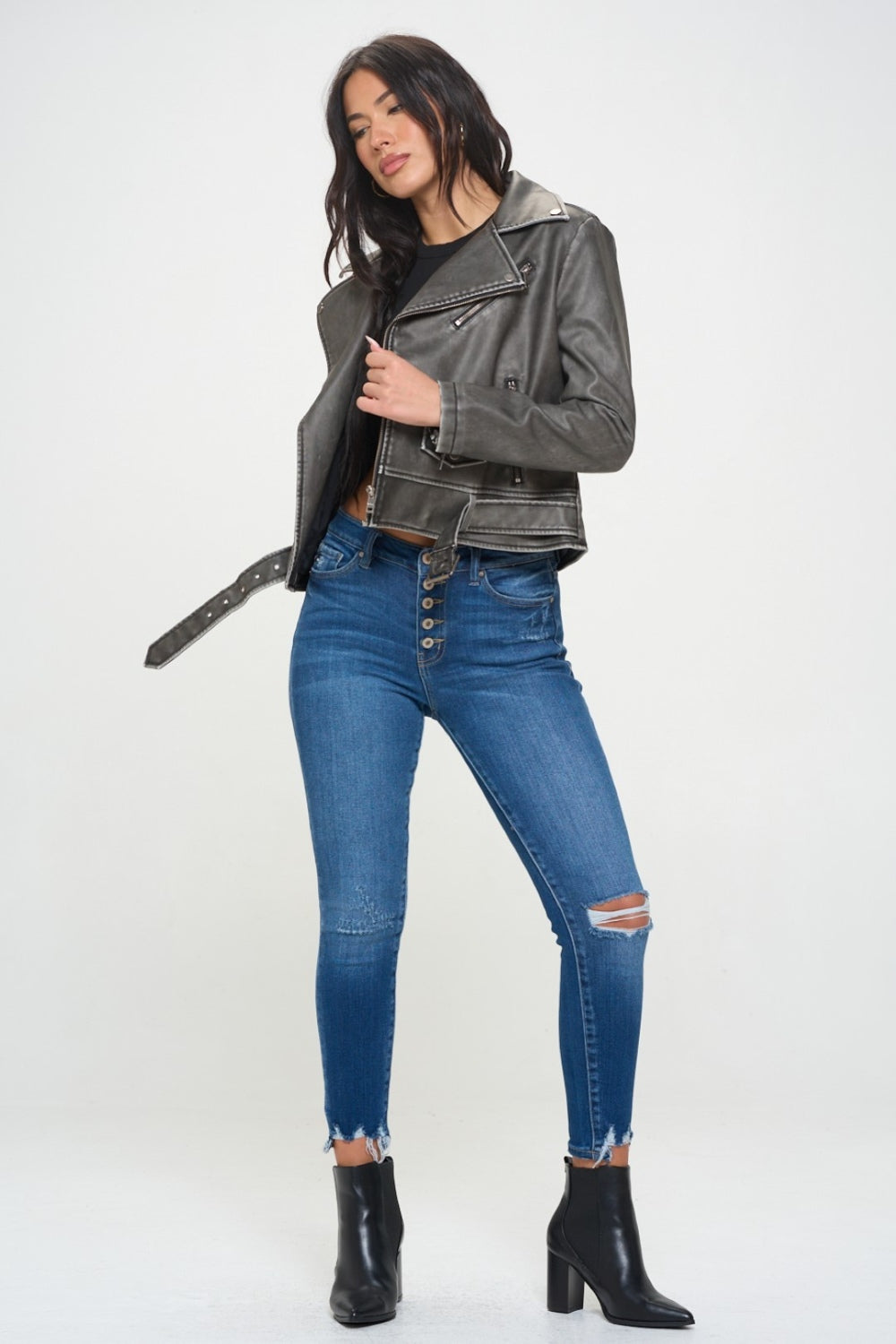 A person wearing a Coalition LA Zip Up Biker Jacket with Belt featuring a notched lapel, paired with blue jeans, stands against a plain background.