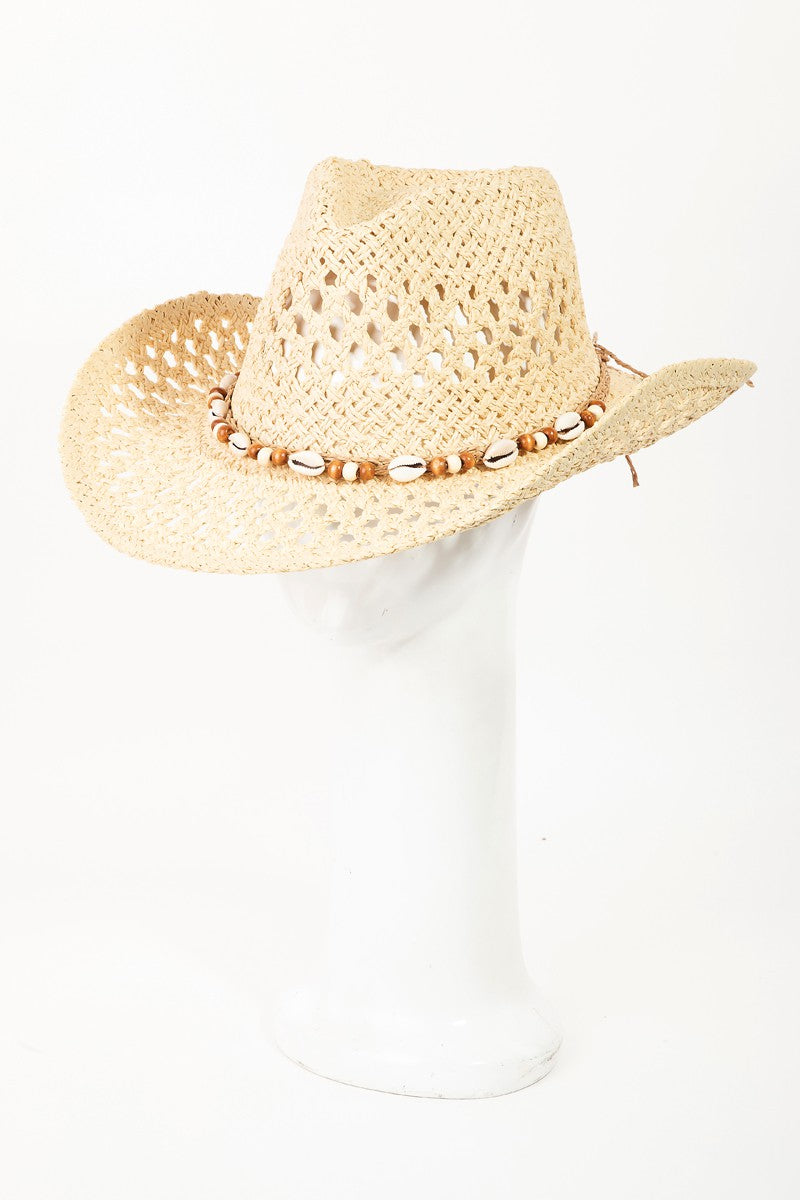 The Fame Cowrie Shell Beaded String Straw Hat, featuring cowrie shells and decorative beads, sits elegantly on a white mannequin head.