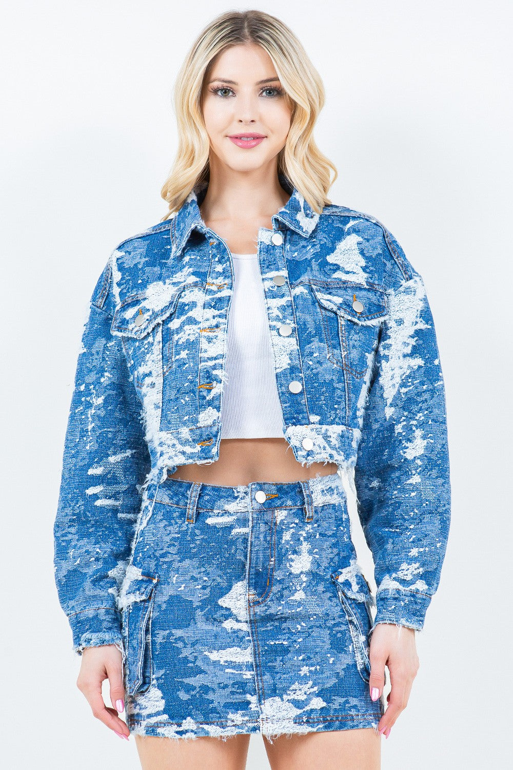 A person wearing the American Bazi Jacquard Trim Cropped Denim Jacket in blue and white distressed denim, paired with a matching skirt, stands against a plain background.