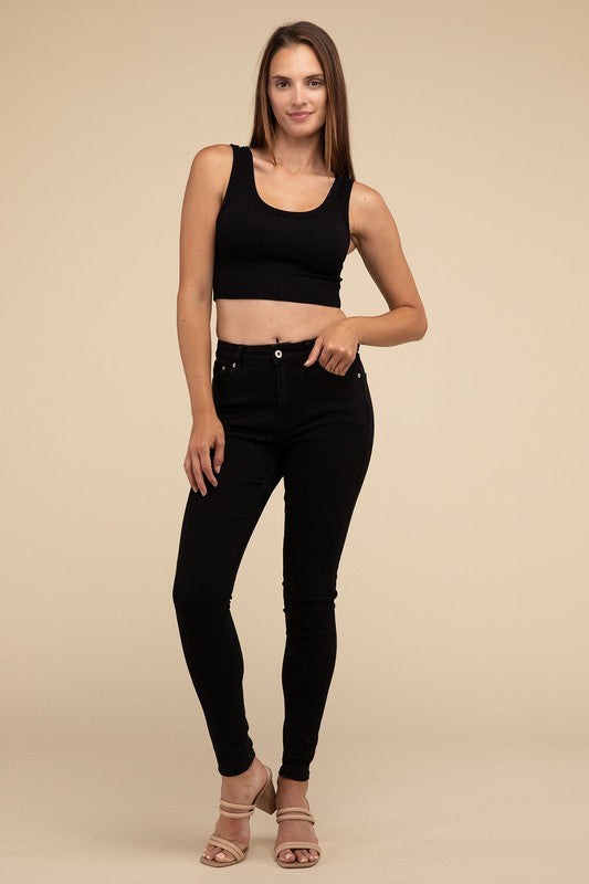 A person with long brown hair wearing the Ribbed Seamless Crop Top in light blue and black pants stands against a beige background, showcasing a perfect summer essential.