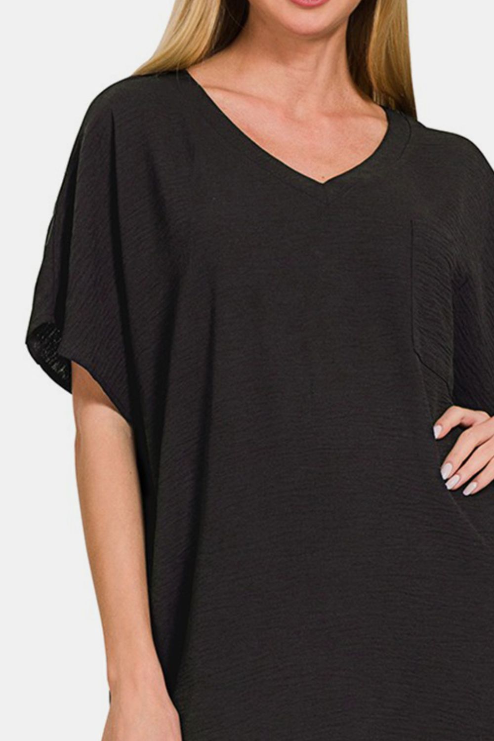 A woman with long hair is sporting the Zenana V-Neck Tee Dress with Pockets, a comfortable, loose-fitting black dress featuring short sleeves. She is smiling and has one hand on her hip.