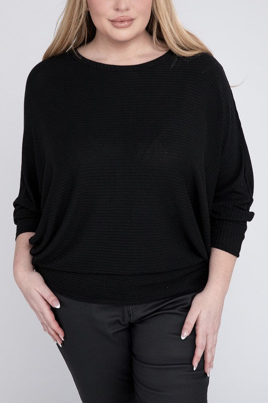 A woman wearing a Plus Ribbed Batwing Long Sleeve Boat Neck Sweater in red and black pants, standing and posing with her hand on her neck, smiling gently at the camera.